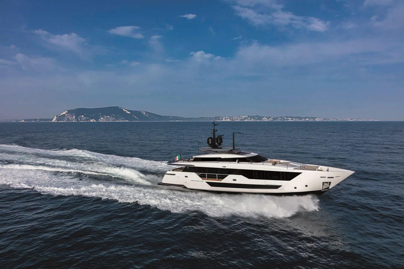 A sleek yacht cruises swiftly across the open sea under a clear blue sky. aboard CUSTOM LINE SAETTA 128/02 Yacht for Sale