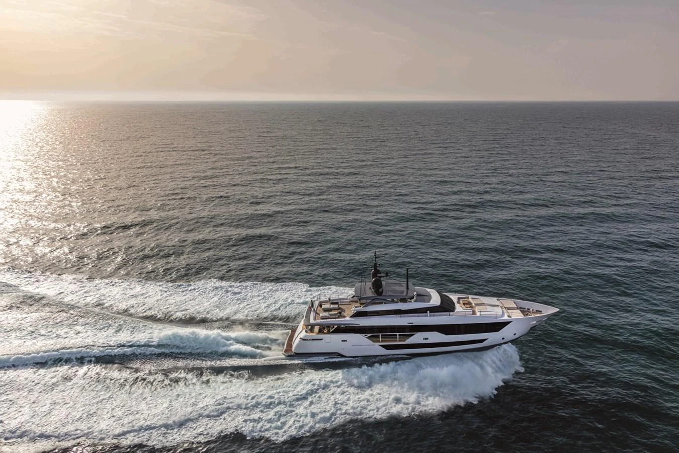 A sleek yacht cruises through open waters at sunset. aboard CUSTOM LINE SAETTA 128/02 Yacht for Sale