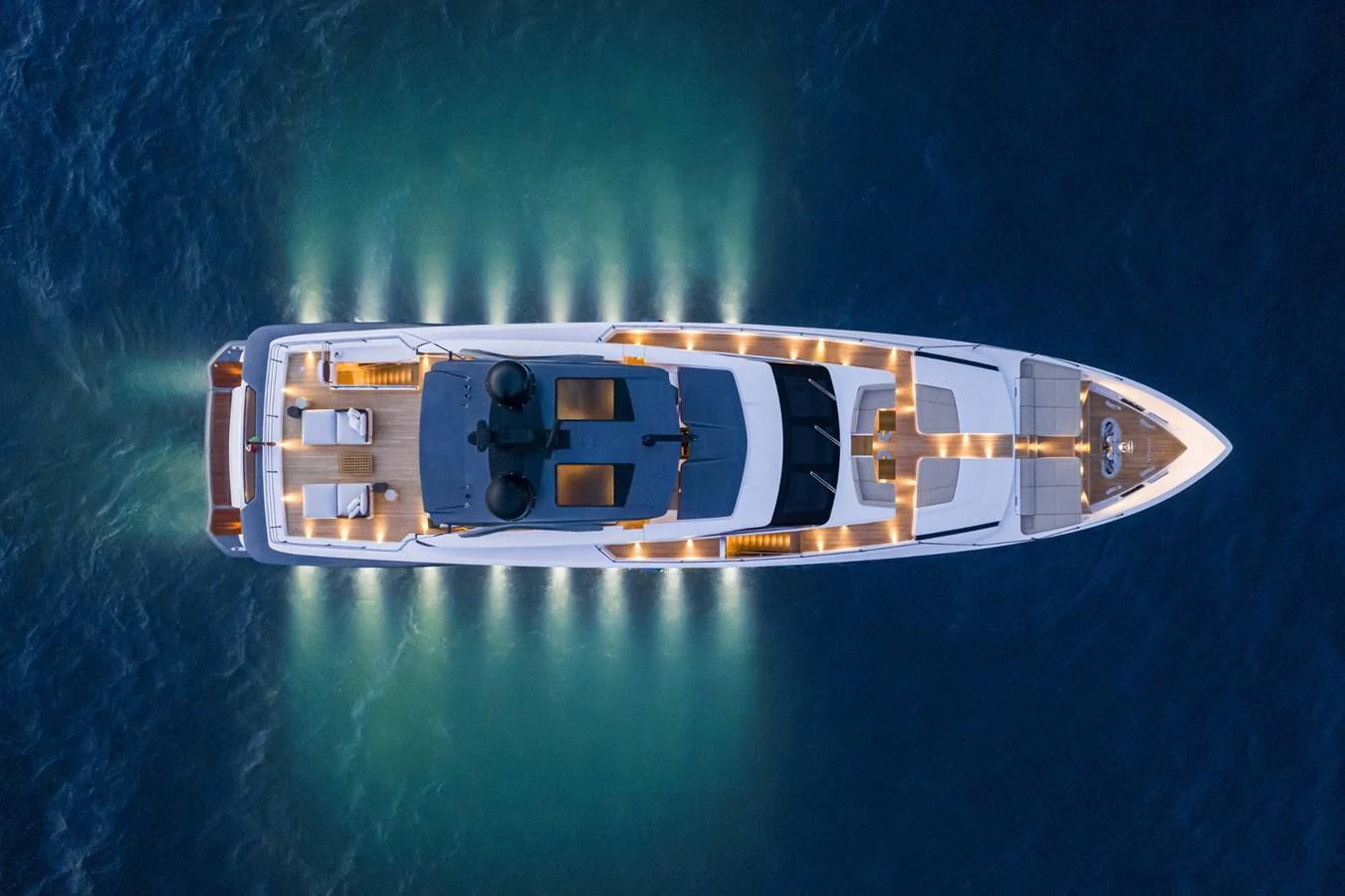 A stunning aerial view of a yacht illuminated against the dark water, showcasing its sleek design and elegant lighting. aboard CUSTOM LINE SAETTA 128/02 Yacht for Sale
