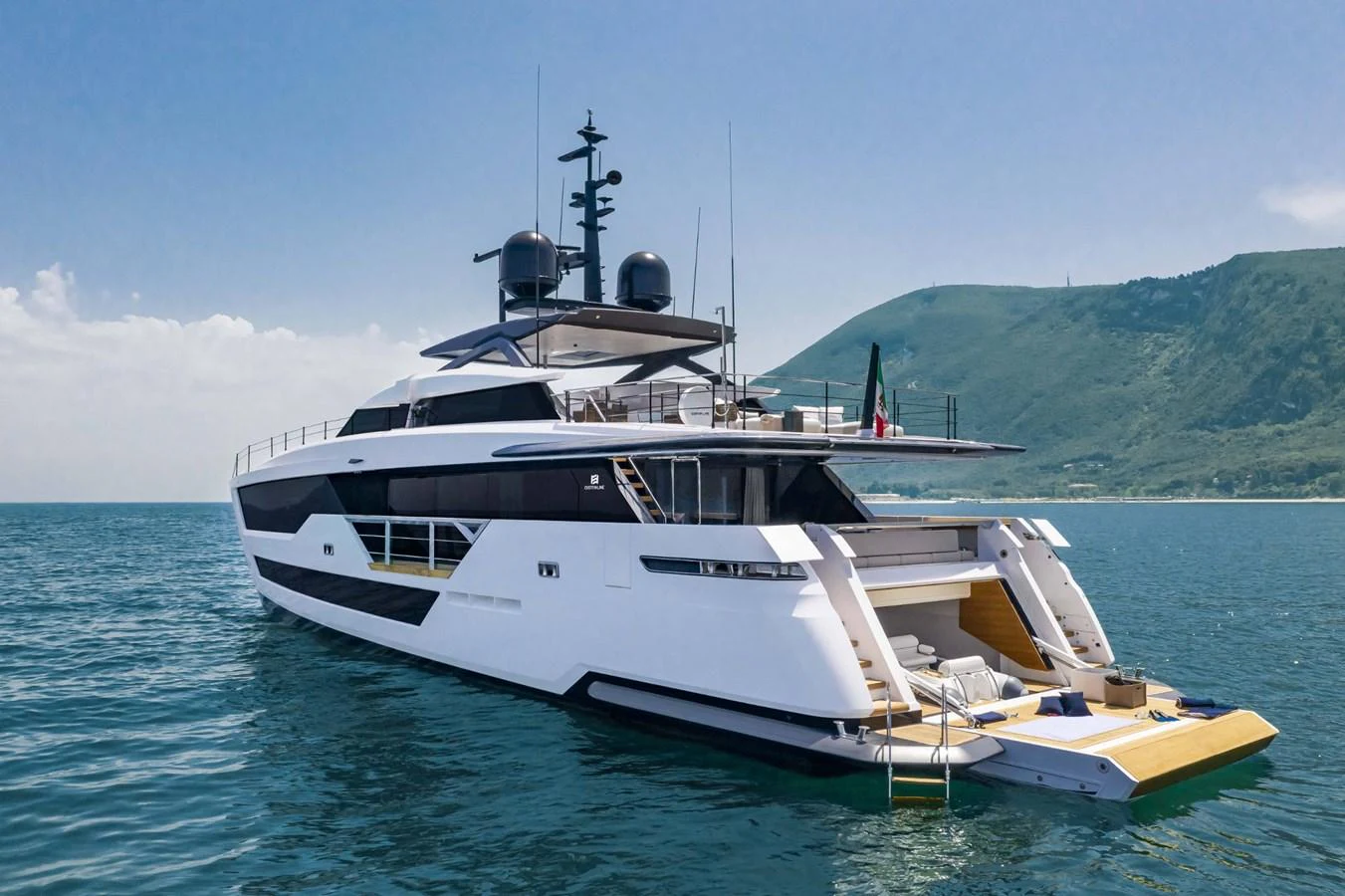 A sleek and modern yacht cruising on calm waters with a scenic mountain backdrop. aboard CUSTOM LINE SAETTA 128/02 Yacht for Sale