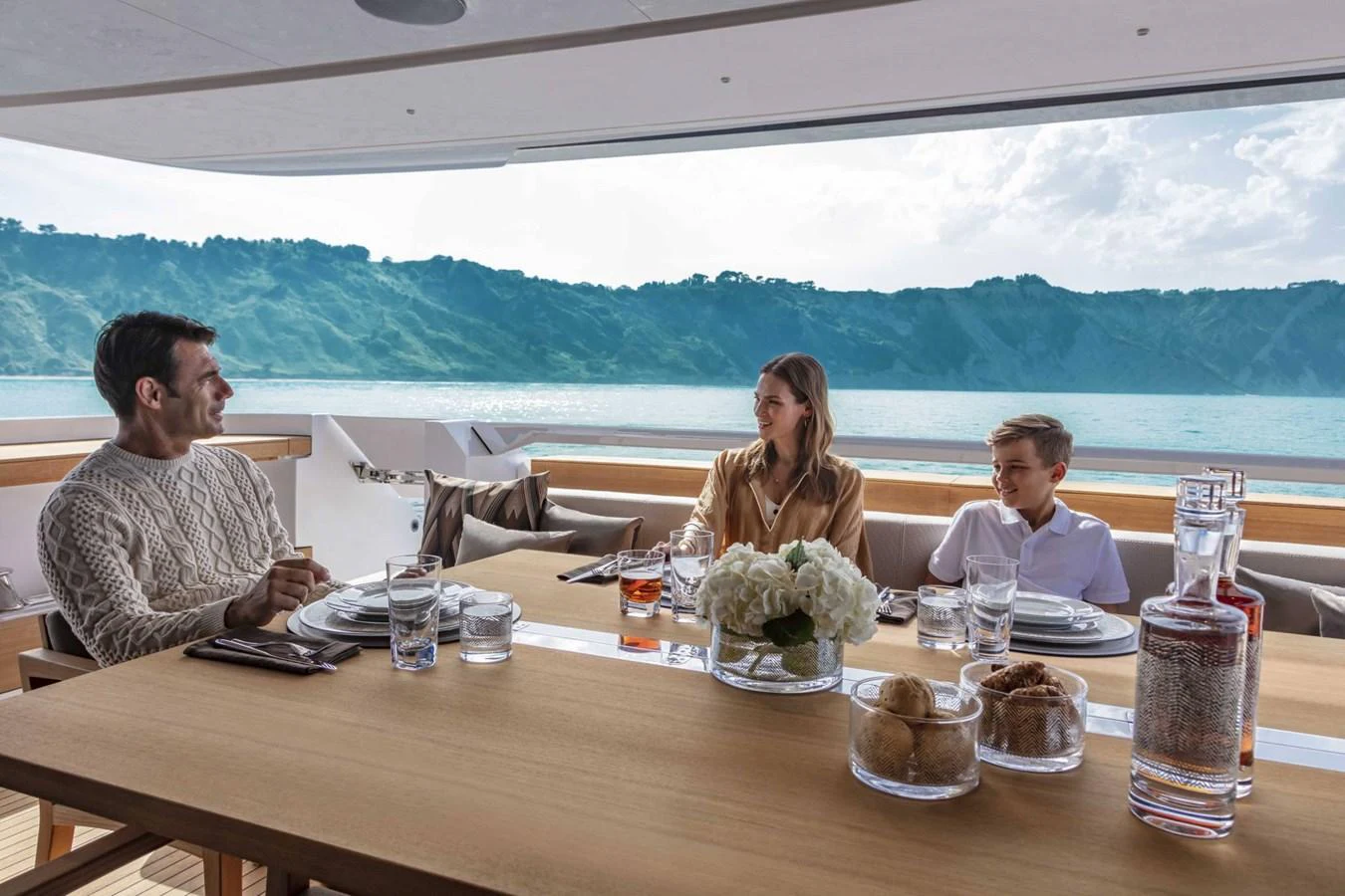 Guests enjoy a meal on the aft deck with stunning ocean views. aboard CUSTOM LINE SAETTA 128/02 Yacht for Sale
