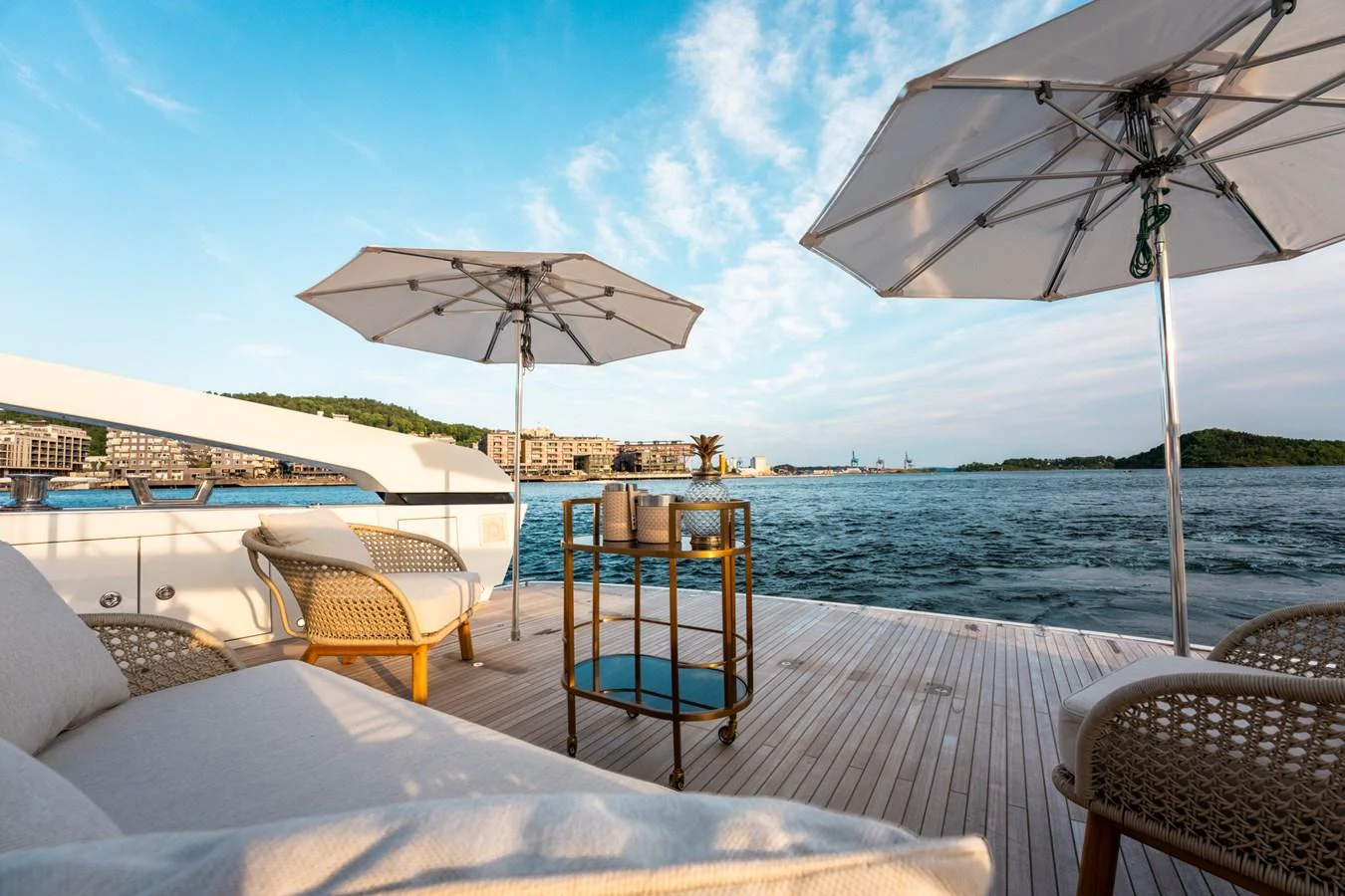 a table and chairs on a deck with umbrellas and a body of water in the background aboard NORTH Yacht for Sale