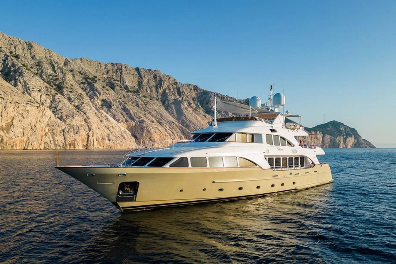 A luxurious yacht cruises along a scenic coastline at sunset. aboard VIRTUE Yacht for Sale