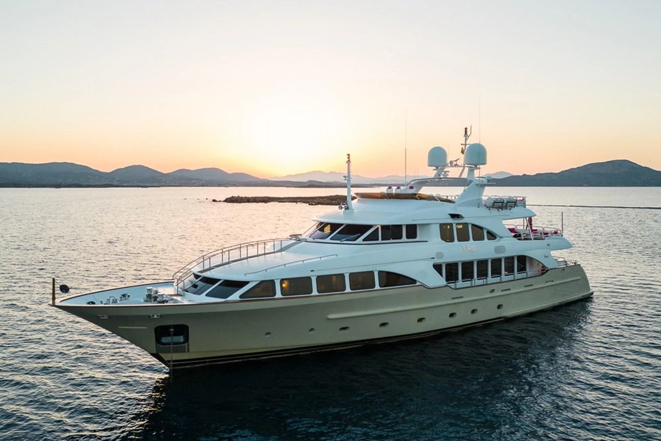A luxurious yacht glides gracefully on the water at sunset, showcasing its elegant design and spacious decks. aboard VIRTUE Yacht for Sale