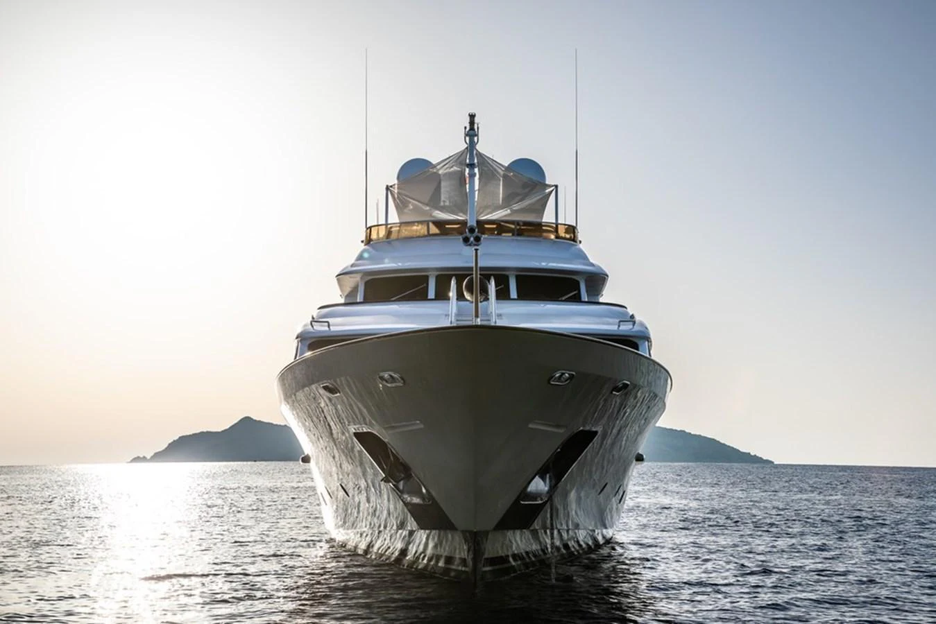 A stunning yacht is captured head-on, gliding gracefully on calm waters at sunset. aboard VIRTUE Yacht for Sale