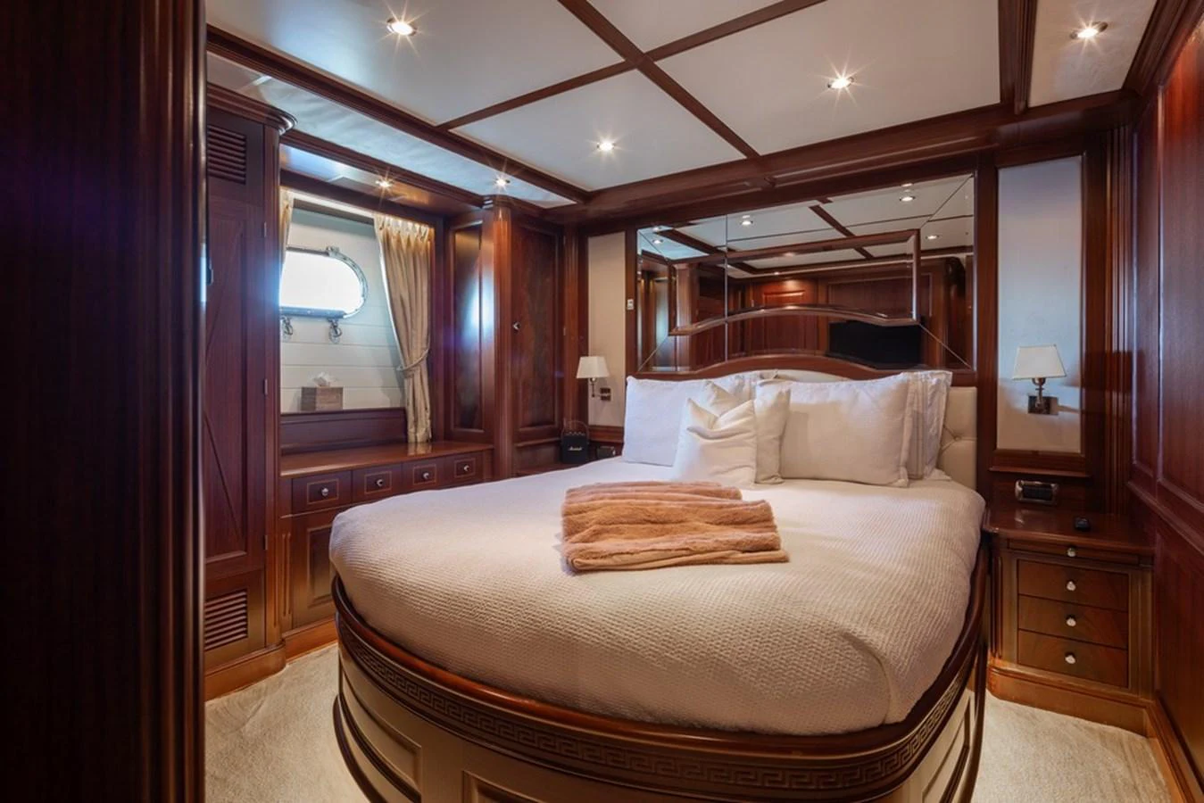 The master stateroom features a luxurious bed with elegant wood paneling and ambient lighting. aboard VIRTUE Yacht for Sale