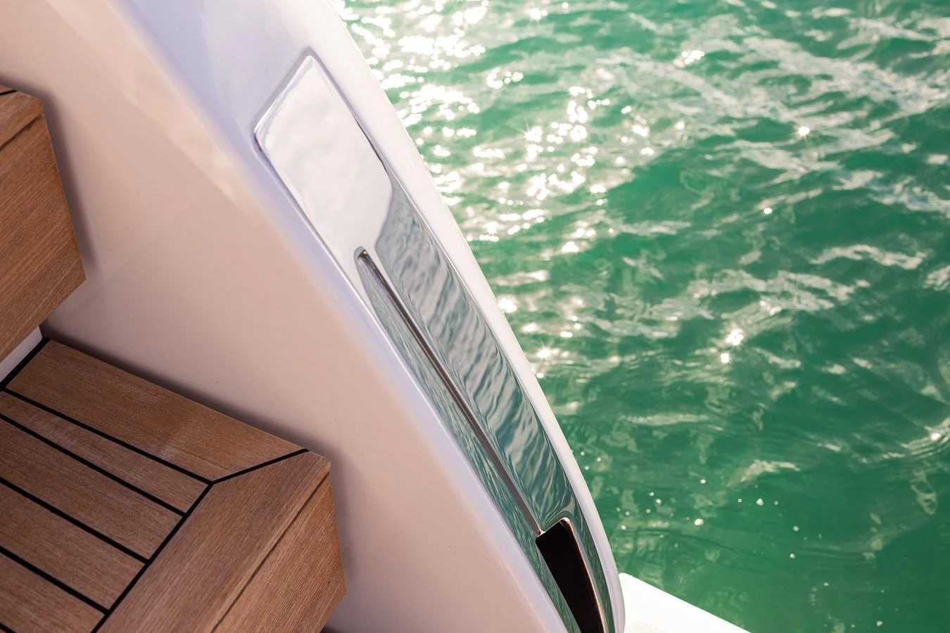 A close-up of a yacht's sleek exterior detail with wooden steps and glistening water in the background. aboard AKULA Yacht for Sale