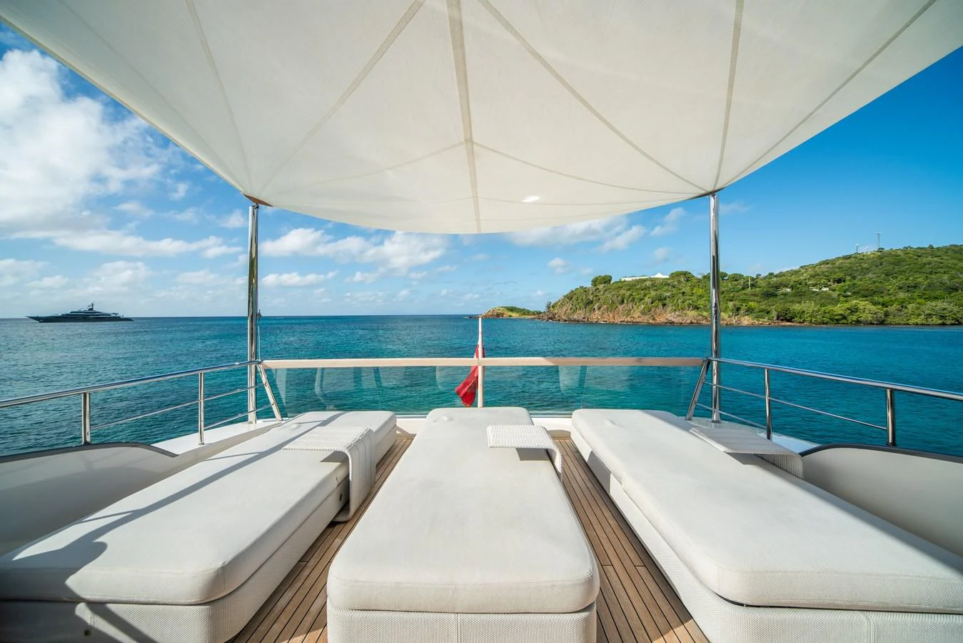 The sundeck offers a serene space with comfortable sun loungers under a shade canopy, overlooking the tranquil sea. aboard AKULA Yacht for Sale