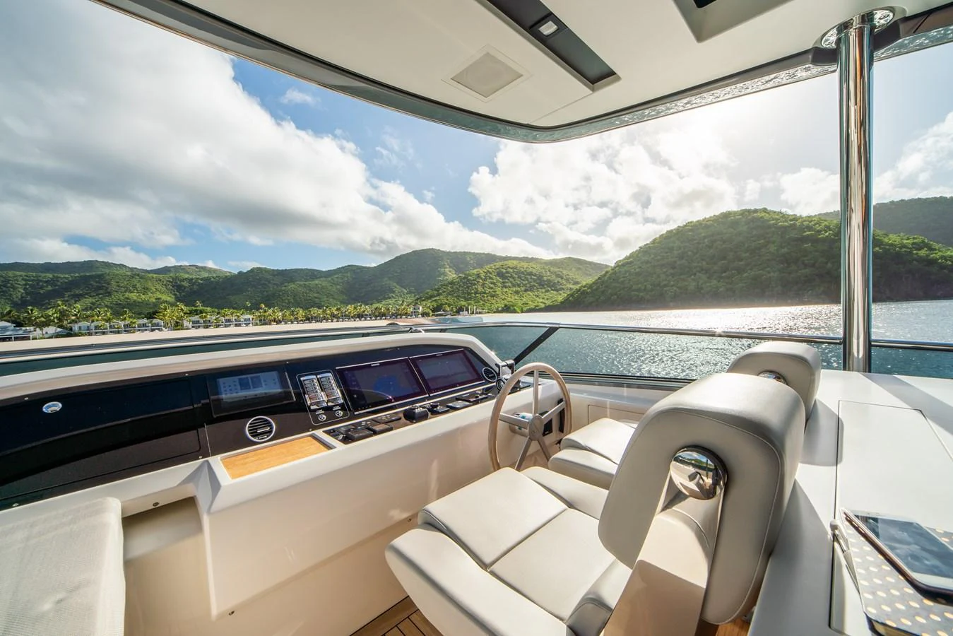 The helm station offers a panoramic view of the serene waters and lush green hills. aboard AKULA Yacht for Sale