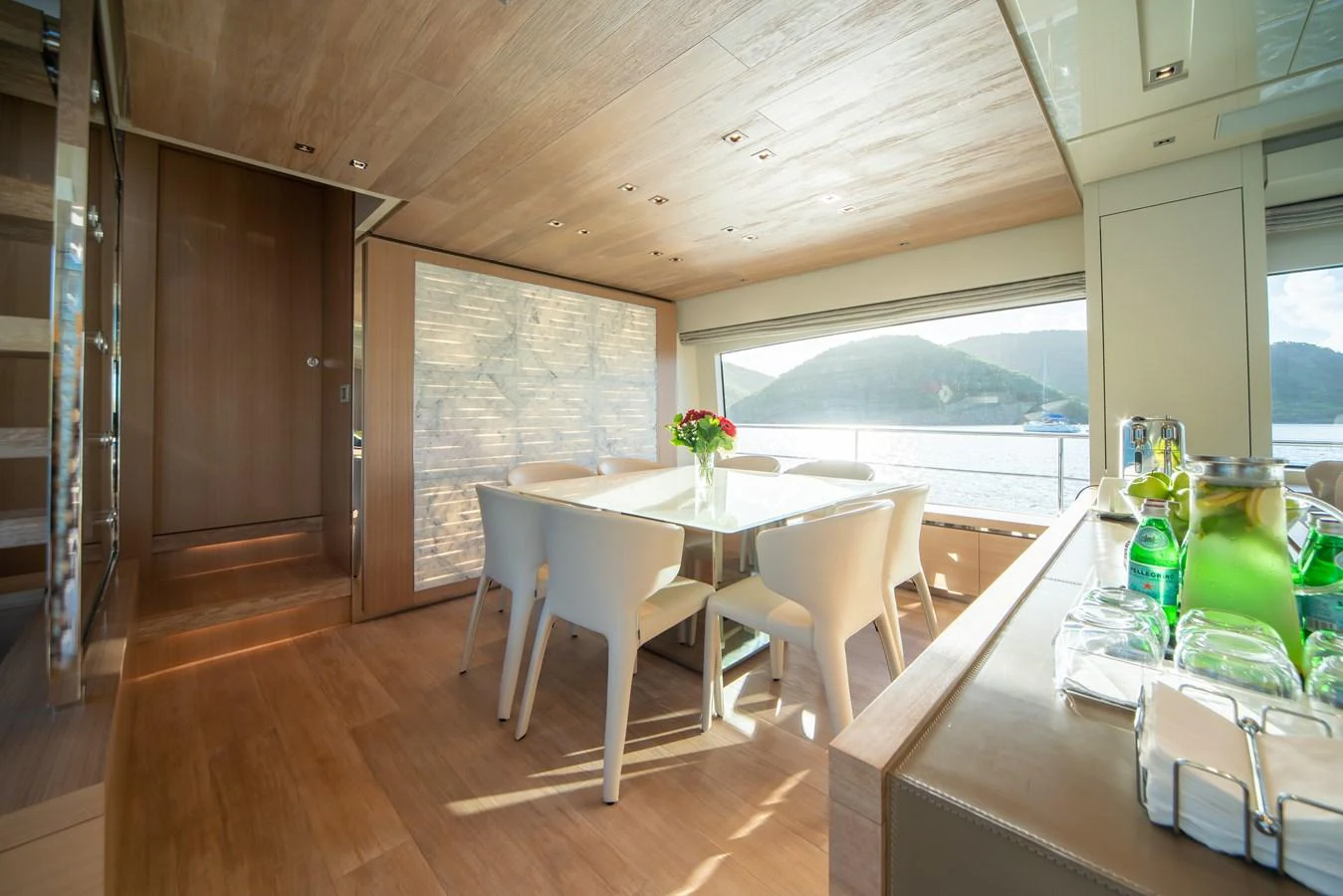 The yacht's dining area features a modern table with elegant seating and a scenic view through large windows. aboard AKULA Yacht for Sale