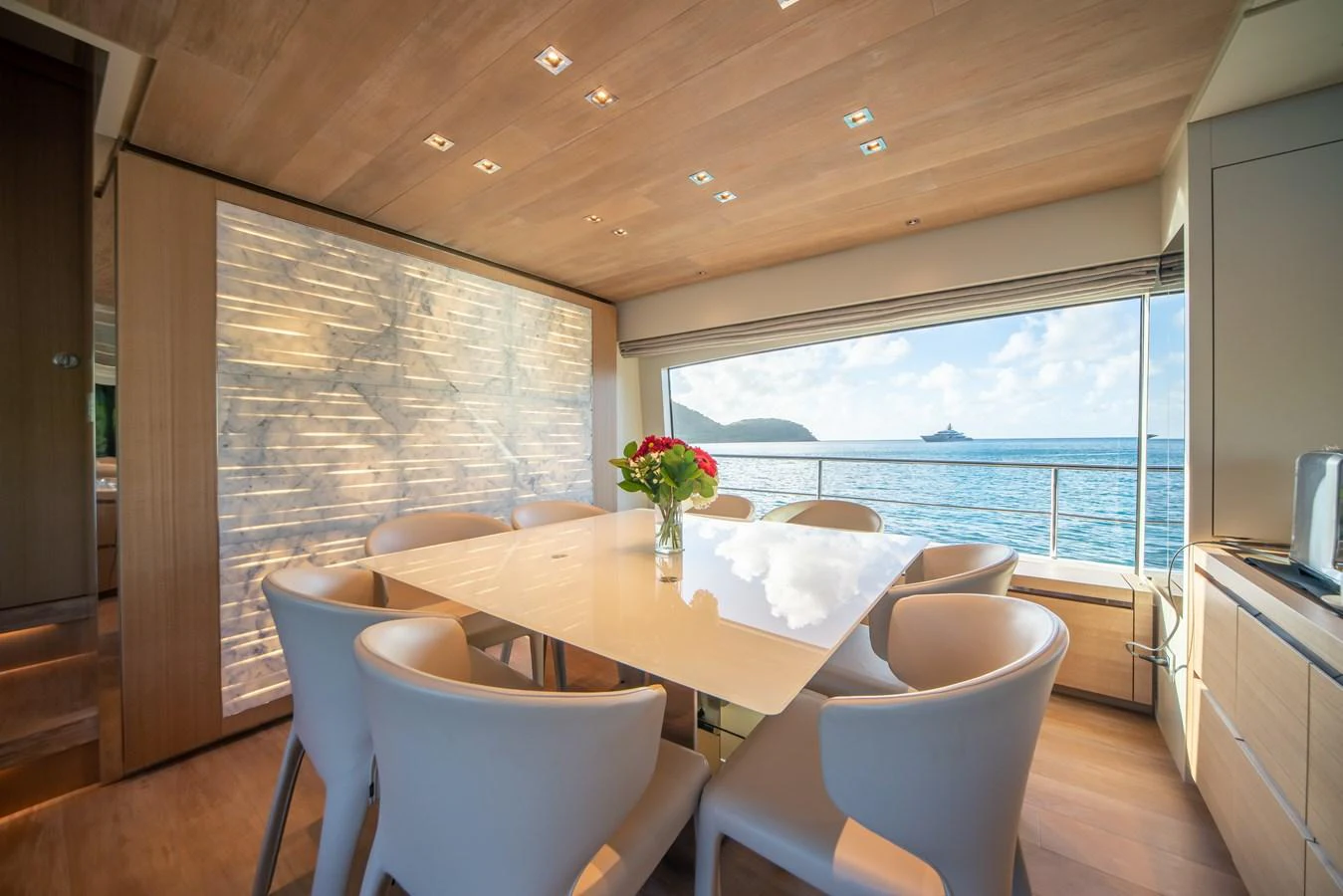 The yacht's dining area offers a serene setting with a large window providing stunning ocean views. aboard AKULA Yacht for Sale