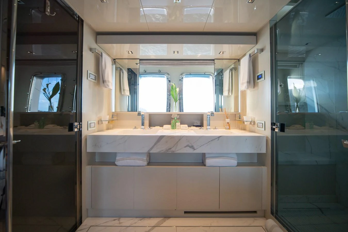 The yacht's bathroom features a luxurious double sink vanity with elegant marble countertops and ample natural light. aboard AKULA Yacht for Sale