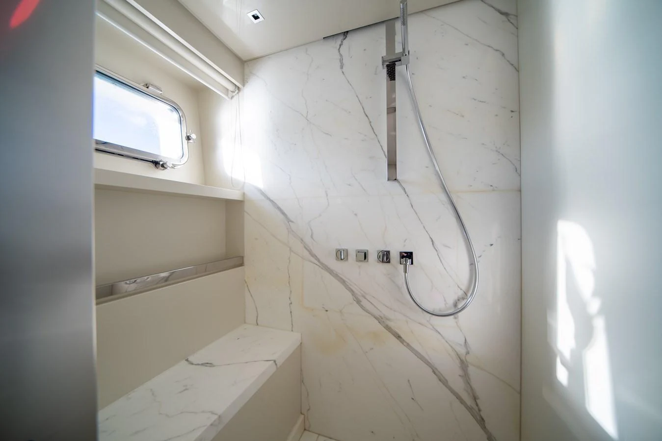 A sleek and modern yacht bathroom with marble walls and a contemporary shower fixture. aboard AKULA Yacht for Sale