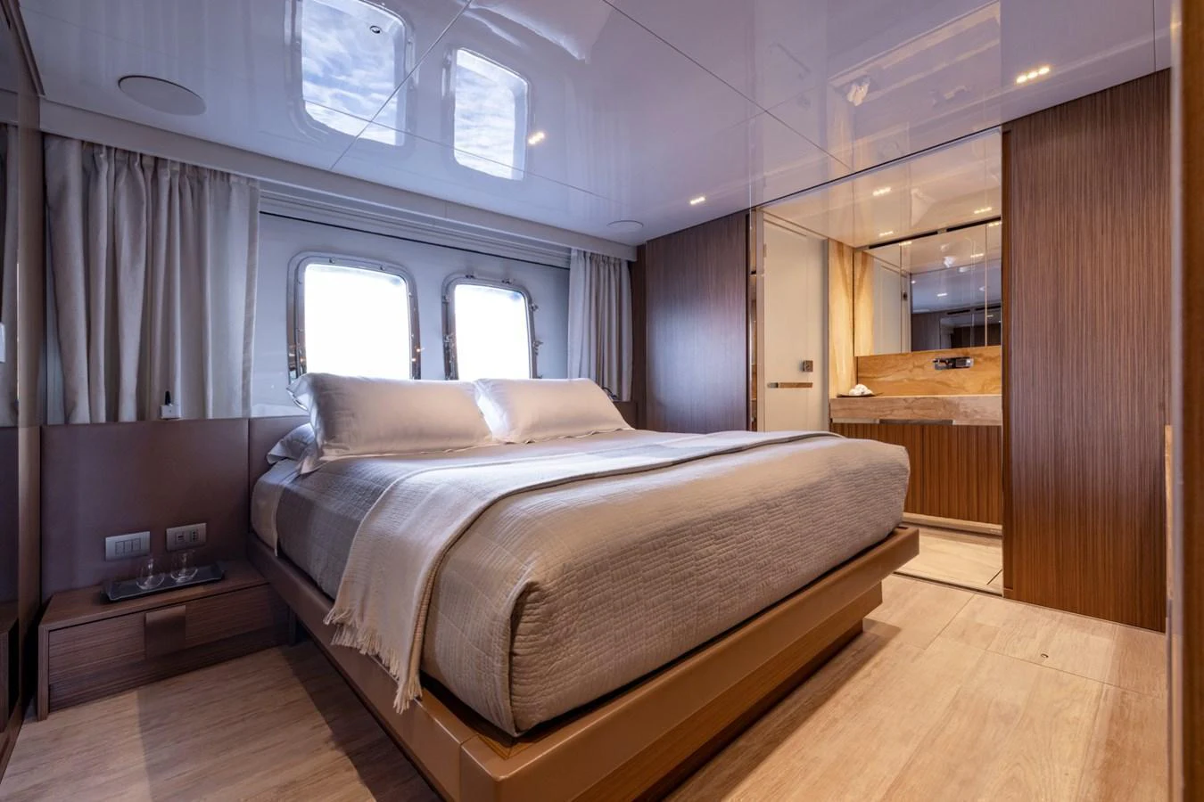The stateroom features a luxurious bed with ample natural light from the windows, complemented by elegant wood finishes. aboard LADY LU' Yacht for Sale