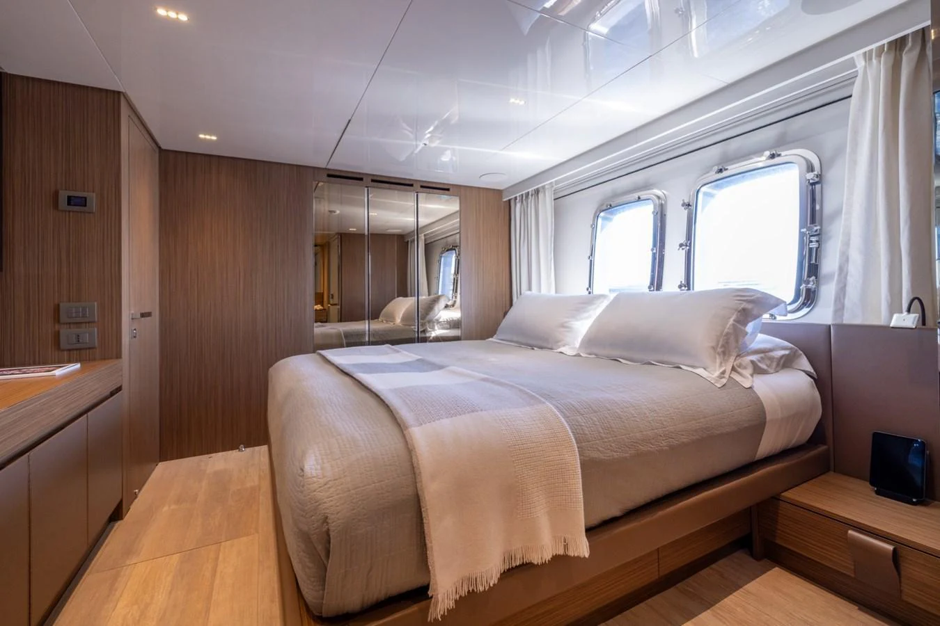 A luxurious stateroom featuring a large bed, wooden accents, and ample natural light from the windows. aboard LADY LU' Yacht for Sale
