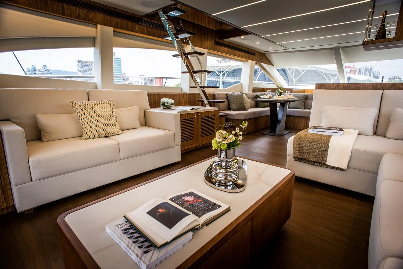 a living room with a book on a coffee table aboard 70' JOHNSON SKYLOUNGE 2026 Yacht for Sale