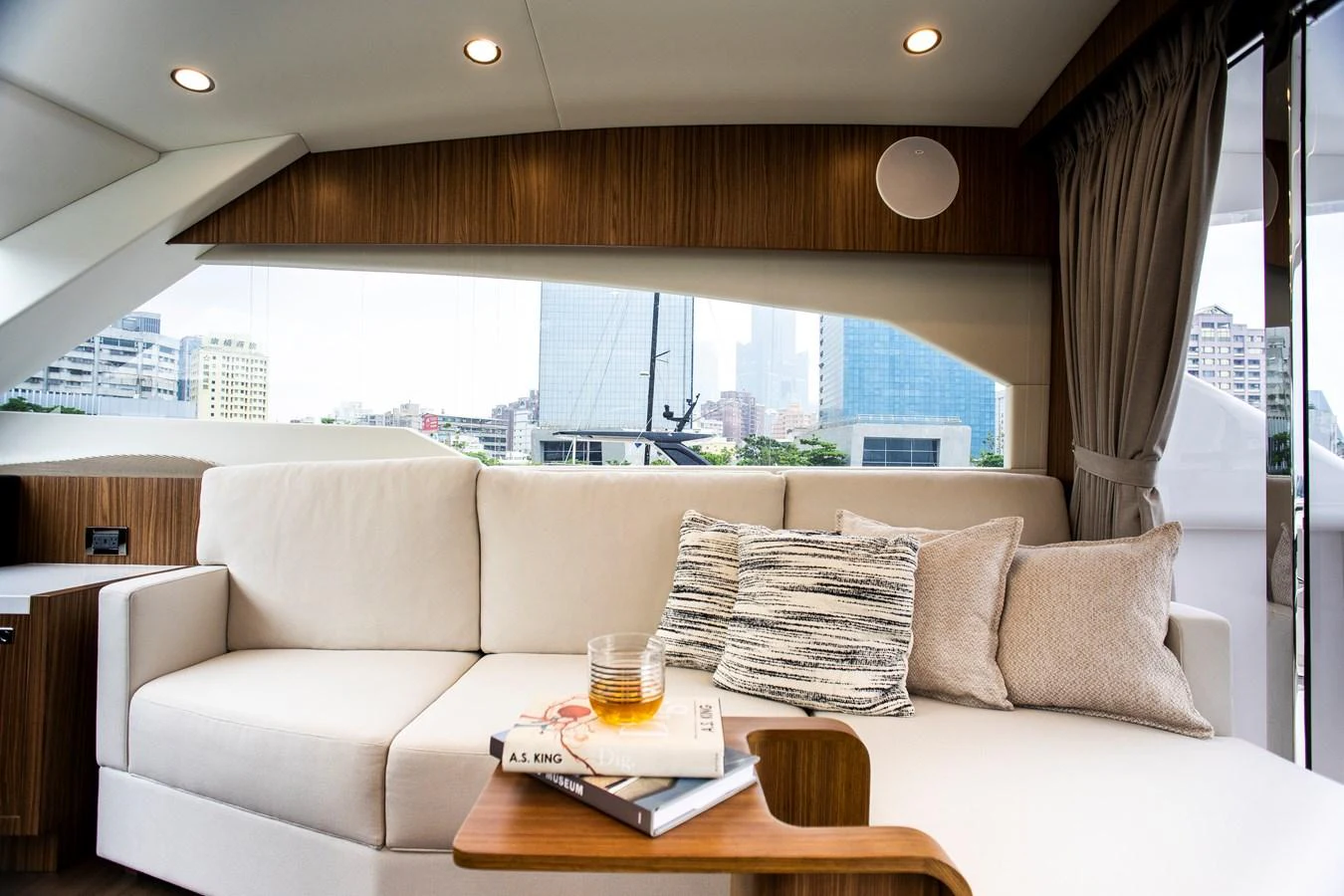 a room with a couch and a table with a glass of beer aboard 70' JOHNSON SKYLOUNGE 2026 Yacht for Sale