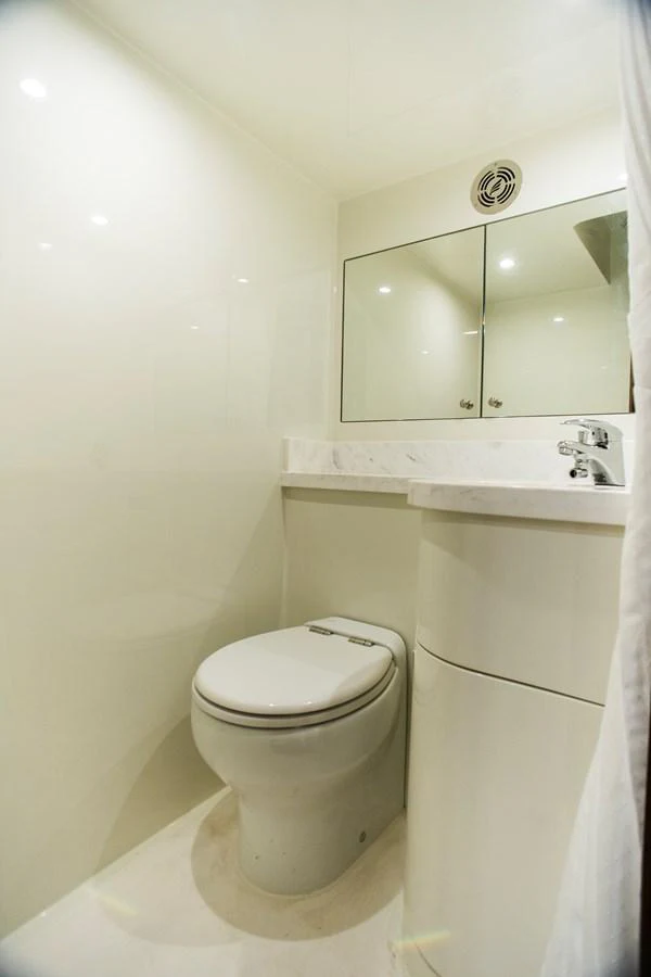a toilet with a mirror above it aboard 70' JOHNSON SKYLOUNGE 2026 Yacht for Sale