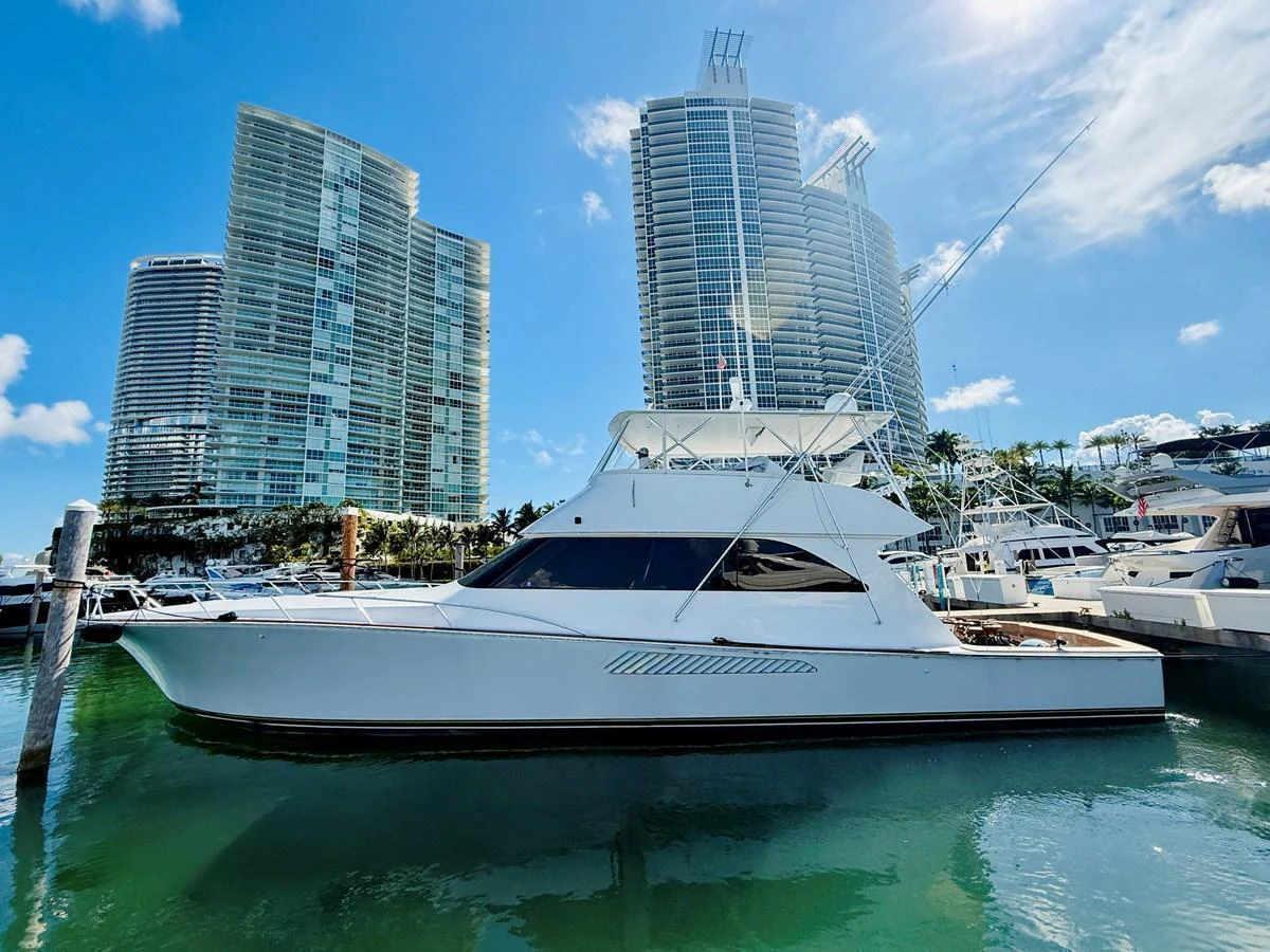 A sleek yacht is docked in a marina with modern high-rise buildings in the background. aboard KICKBACK Yacht for Sale
