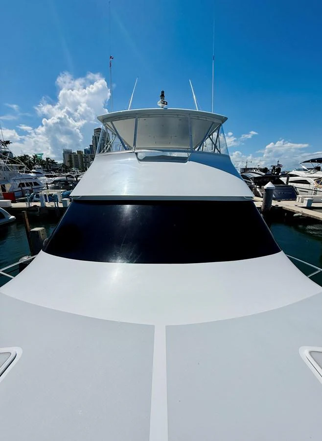 A sleek yacht docked at a marina under a clear blue sky. aboard KICKBACK Yacht for Sale