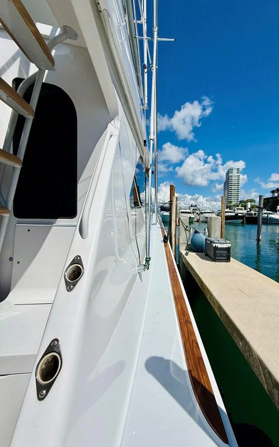 The yacht is docked at a marina on a sunny day, showcasing its sleek exterior and polished deck. aboard KICKBACK Yacht for Sale