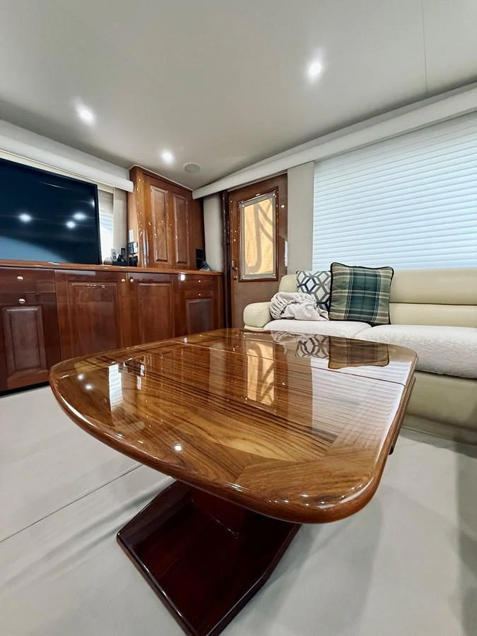 The yacht's salon features a polished wooden table, comfortable seating, and a large TV. aboard KICKBACK Yacht for Sale