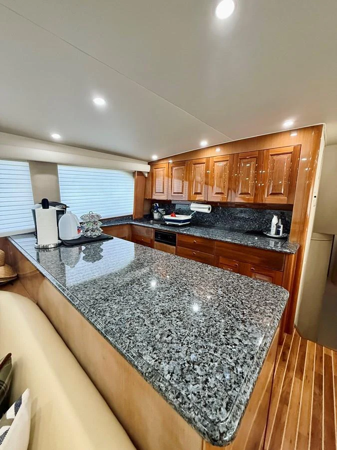 The yacht's galley features a sleek granite countertop and polished wooden cabinetry. aboard KICKBACK Yacht for Sale