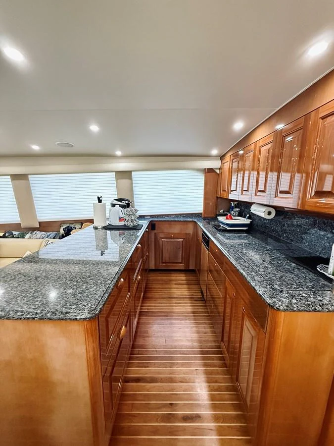 The yacht's galley features polished wooden cabinetry and sleek granite countertops, creating a refined and functional space. aboard KICKBACK Yacht for Sale