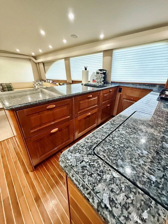 The yacht's galley features luxurious granite countertops and rich wooden cabinetry, creating a sophisticated and functional space. aboard KICKBACK Yacht for Sale