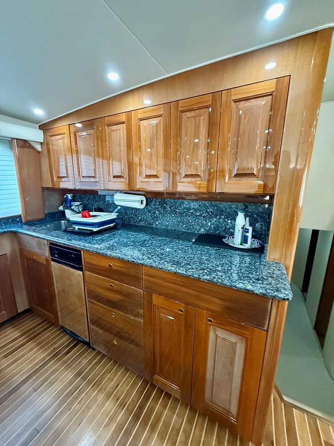 The yacht's galley features polished wooden cabinetry and a sleek granite countertop. aboard KICKBACK Yacht for Sale