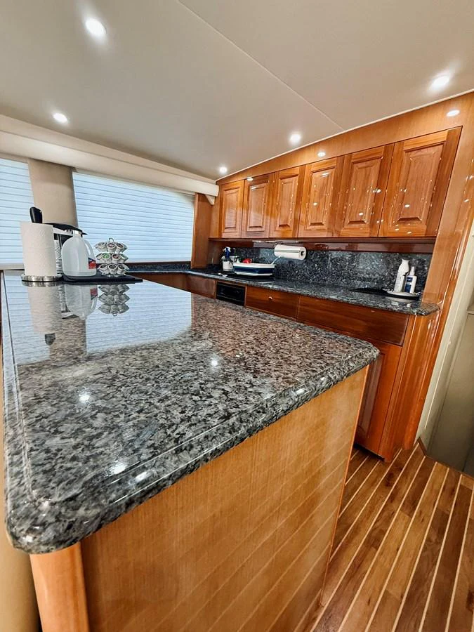 The yacht's galley features elegant wooden cabinetry and a sleek granite countertop. aboard KICKBACK Yacht for Sale