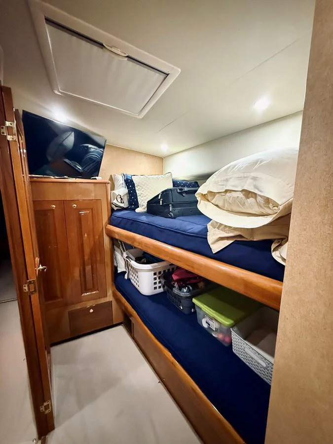 The cozy bunk room features neatly arranged beds with storage space underneath. aboard KICKBACK Yacht for Sale