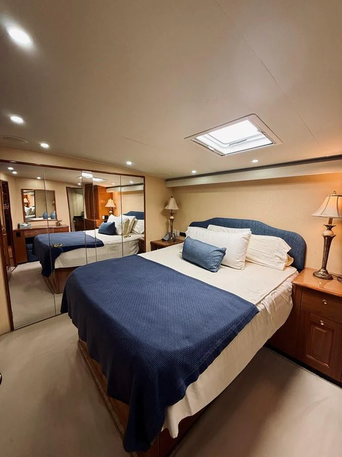The stateroom features a comfortable bed with elegant bedding and ample lighting. aboard KICKBACK Yacht for Sale
