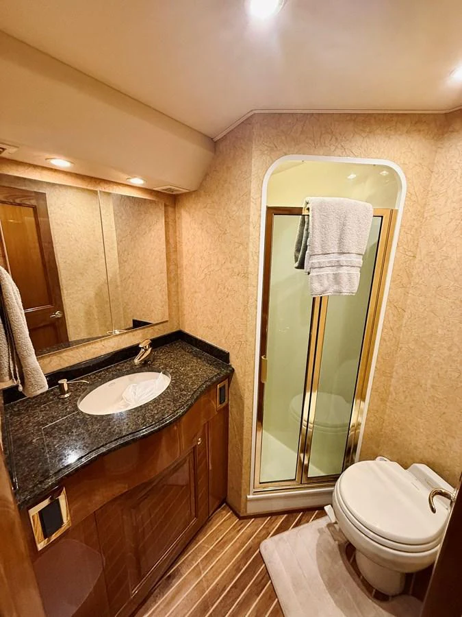 The yacht's bathroom features a sleek design with a granite countertop and a glass-enclosed shower. aboard KICKBACK Yacht for Sale