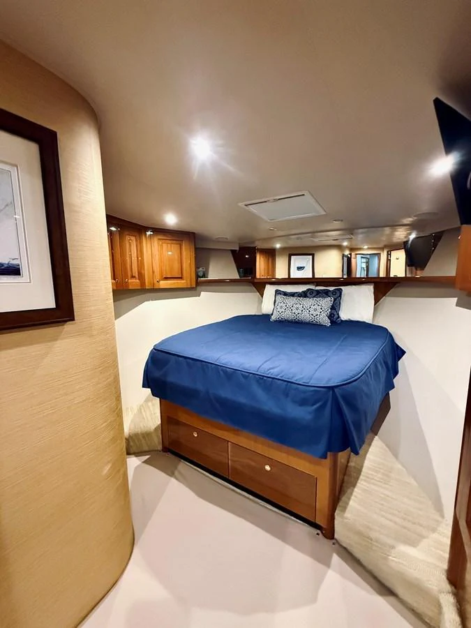 A cozy stateroom featuring a comfortable bed with blue bedding and ample storage space. aboard KICKBACK Yacht for Sale