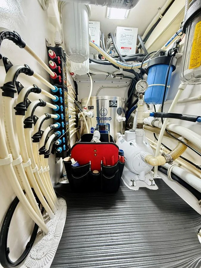 The image showcases a well-organized engine room with various mechanical and plumbing components. aboard KICKBACK Yacht for Sale