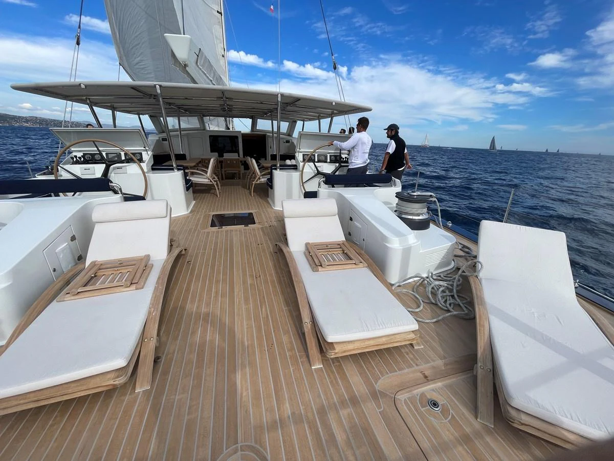 The aft deck features luxurious sun loungers and a spacious seating area under a shaded canopy. aboard MUMU Yacht for Sale
