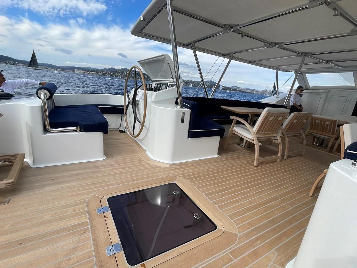 The aft deck features a spacious seating area with a helm station and a dining table, perfect for enjoying the open sea. aboard MUMU Yacht for Sale