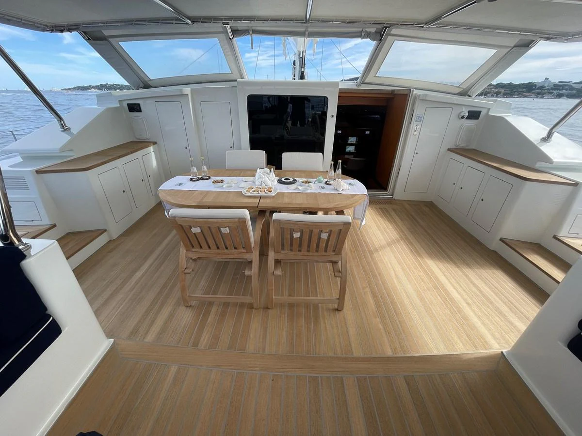 The aft deck features a stylish dining area with a wooden table and chairs, perfect for alfresco meals. aboard MUMU Yacht for Sale
