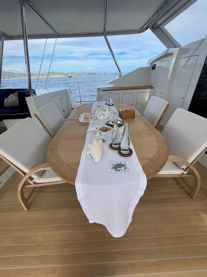 The aft deck features an elegant dining setup with a scenic ocean view. aboard MUMU Yacht for Sale