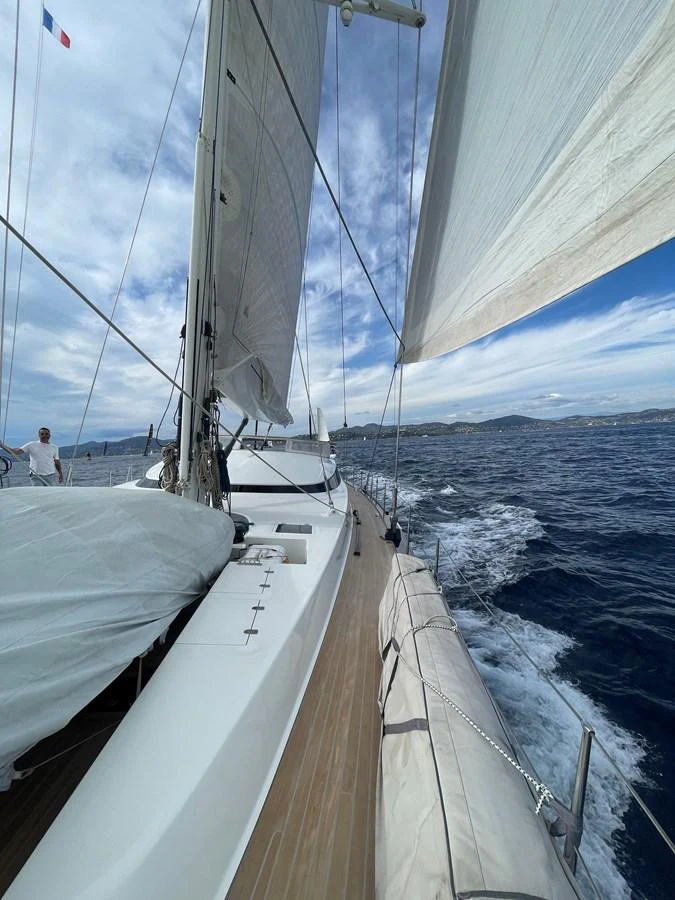 A sleek sailing yacht glides through the water under full sail on a clear day. aboard MUMU Yacht for Sale