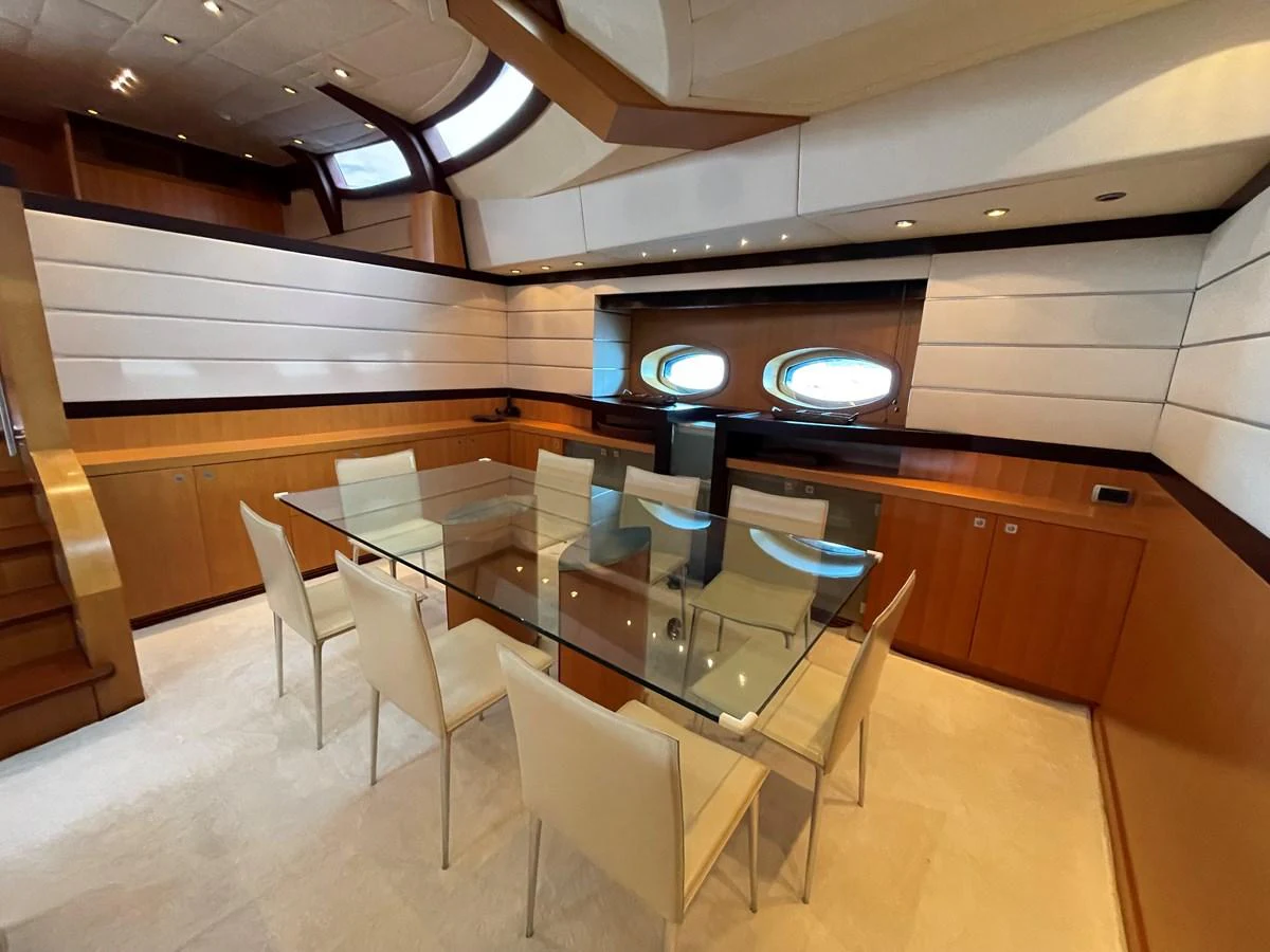 The yacht's dining area features a sleek glass table surrounded by modern chairs, creating an elegant and inviting space. aboard MUMU Yacht for Sale