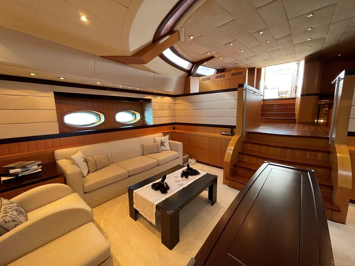 The salon features a cozy seating area with elegant furnishings and ample natural light. aboard MUMU Yacht for Sale