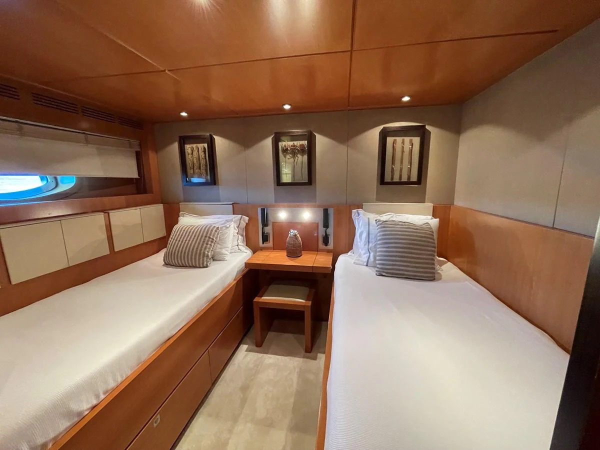 The twin stateroom features two single beds with elegant bedding and tasteful decor. aboard MUMU Yacht for Sale