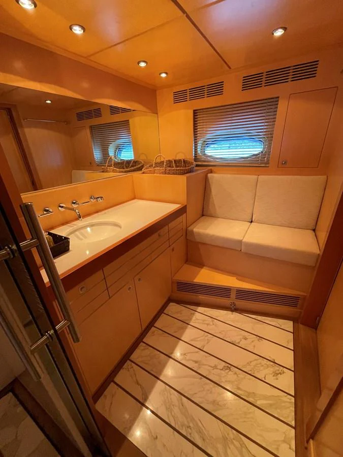 The yacht's bathroom features a sleek design with wooden cabinetry and a comfortable seating area. aboard MUMU Yacht for Sale