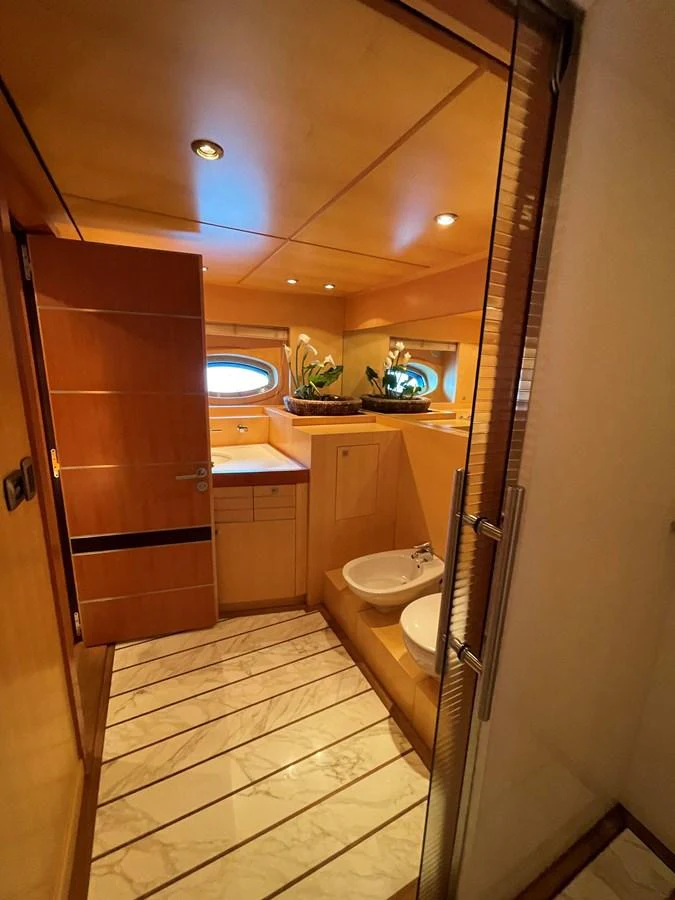 The yacht's bathroom features warm wood tones and modern fixtures, creating a cozy and elegant space. aboard MUMU Yacht for Sale