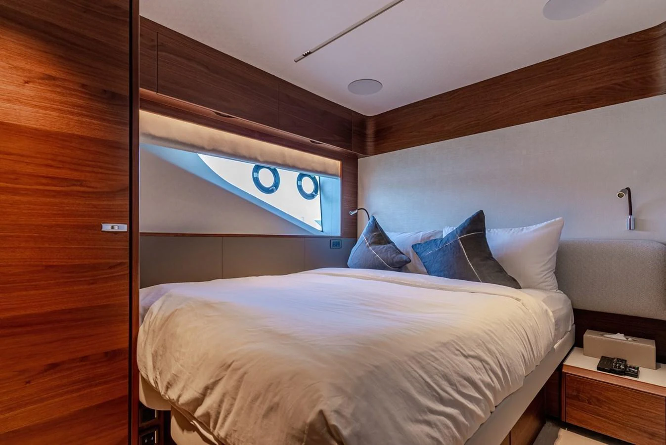 The stateroom features a cozy bed with plush pillows and warm wooden accents. aboard SEMIA Yacht for Sale