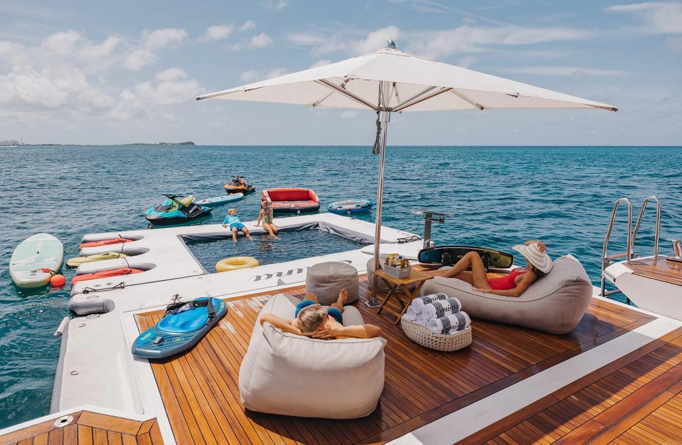 The aft deck features a luxurious lounging area with bean bags, an umbrella, and easy access to water toys. aboard EMINA Yacht for Sale