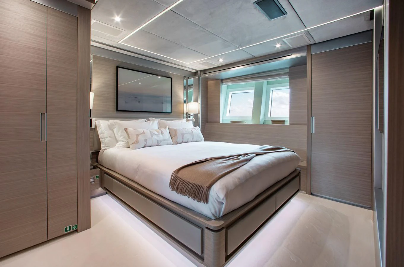 The stateroom features a luxurious bed with modern decor and ample natural light. aboard EMINA Yacht for Sale