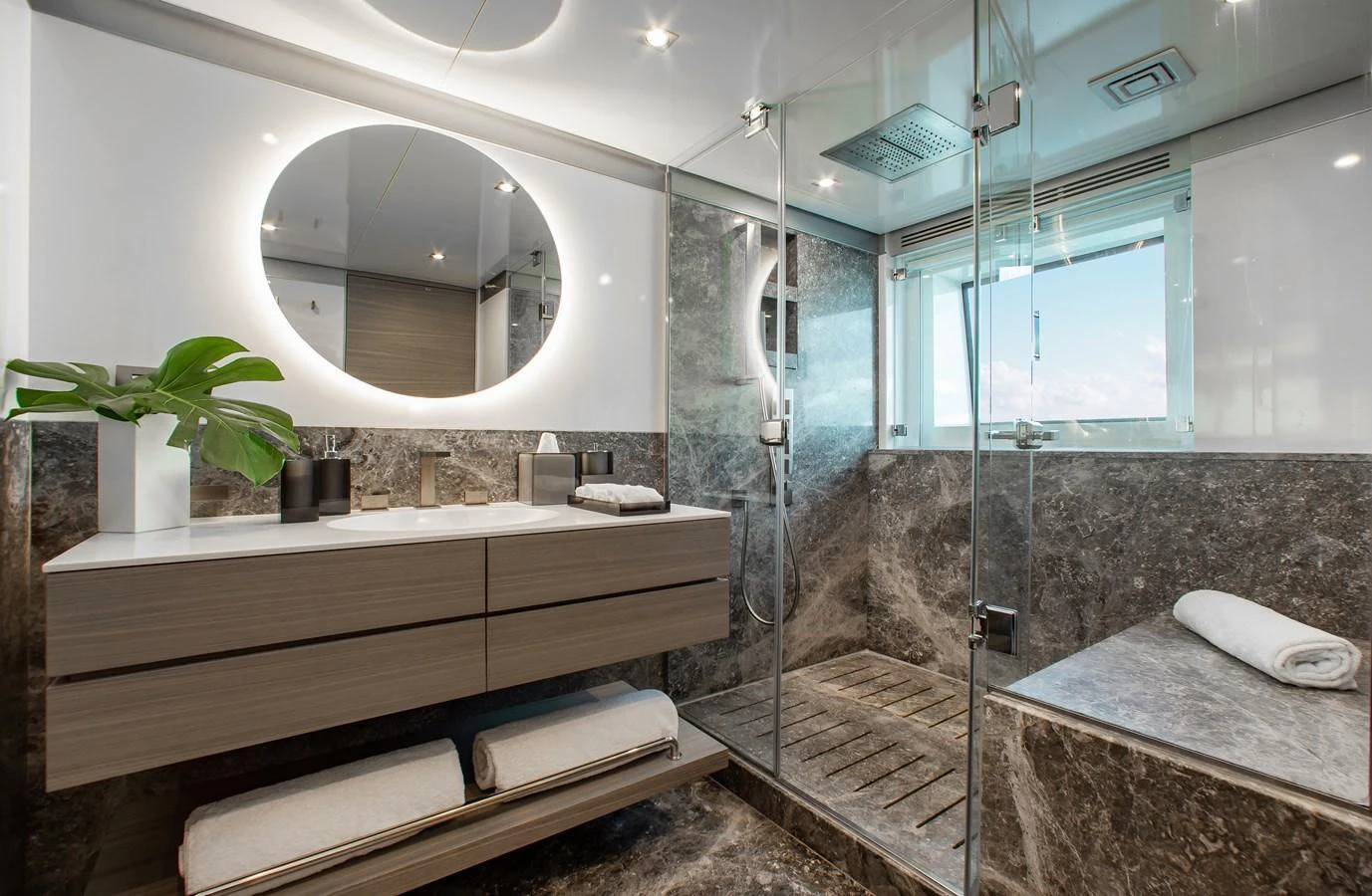 A luxurious yacht bathroom featuring a modern vanity, glass-enclosed shower, and elegant marble finishes. aboard EMINA Yacht for Sale